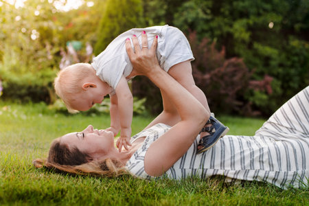 happy harmonious family outdoors. mother raises her baby up, laughs and plays in the summer on...