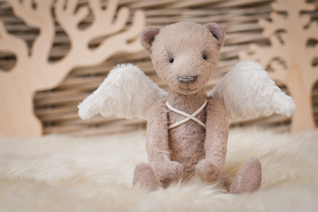 A teddy bear with angel wings sits on the background of a wicker basket. Blank form Kindness, hope, keeper,の写真素材
