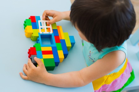 Plastic toy blocks, designer of childrens toys. Bright building blocks in the shape of a heart in childrens hands. Educational toys. Early learning. Concept of love. Window to the heart. beneficenceの写真素材
