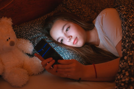 teen girls lying in bed at night and using smartphone. Insomnia and the harm of the smartphone...