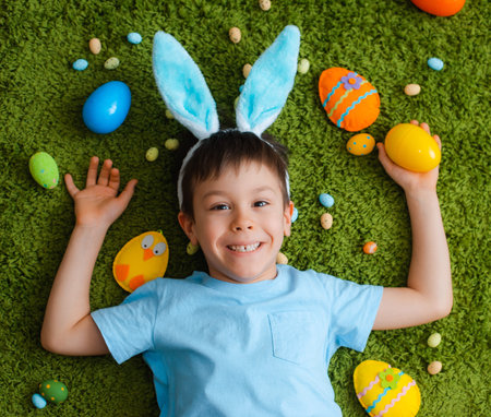 Little boy in bunny ears are playing with Easter eggs. Kids celebrating Easter. Children on Easter...