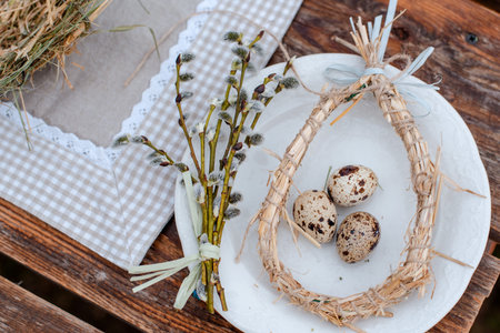 Decorative nest of straw on a plate with Easter quail egg on a served festive table in the garden...