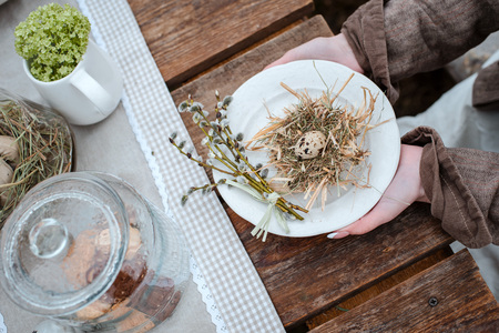 Decorative straw nests with quail egg close-up in female hands on vintage rustic background. Farm. Easter Holiday.の写真素材