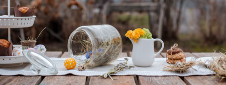 Served festive decorative table in the garden outdoors. Farm. Rustic style. Willow spring bloom. Flowers cookies glass jar. Easterの写真素材