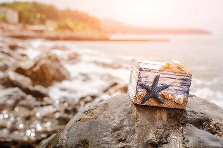 Wooden decorative Chest with sea shells and blue star on the sea coast. Treasures, Souvenirs. Free spaceの写真素材