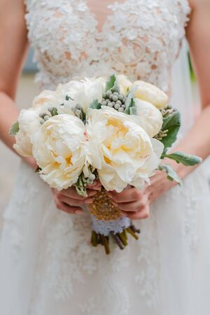 Newly married couple. Wedding day. Bouquet of the bride in the hands, the groom's embrace. Free space.の写真素材