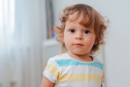 close-up of babys face, cute baby with curly hair. Portrait of a child at home.の写真素材