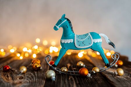 Vintage toy rocking horse on the abstract background of Christmas balls decoration lights and snow. New year, lights, free space, mock-upの写真素材