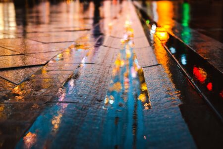Rainy night in a big city, reflections of lights on the wet road surface. The view from the street level. abstract background.の写真素材