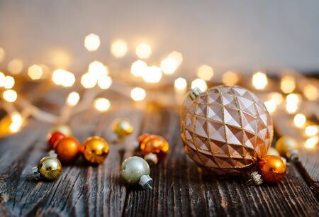 Christmas tree ball toy lay on a wooden table against a bokeh of holiday lights. New year background for greetings. Copy space for text and layoutの写真素材