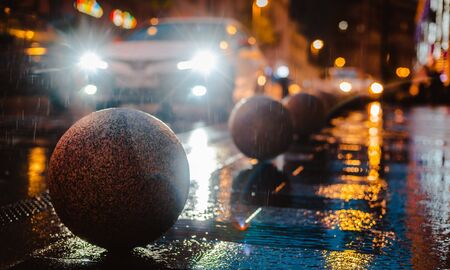 Rainy night in a big city, reflection of colorful city lights on the wet road surface. The view from the street level feet of pedestrians. abstract background. defocused, depth of field, bokehの写真素材