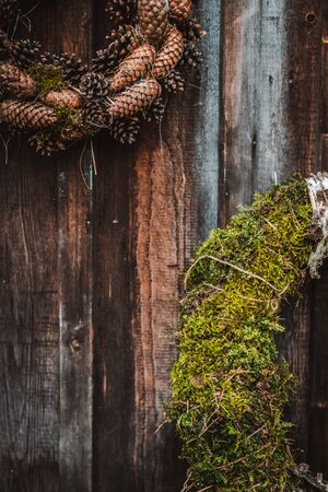 festive rustic wreaths of cones and moss on a dark brown wooden background. Christmas and New year holiday concept. House decoration. free space for text.の写真素材