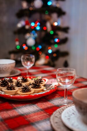 Traditionally decorated Christmas table. Creative decoration of the festive table cones on a plate on the background of bokeh lights. The concept of celebrating the new yearの写真素材
