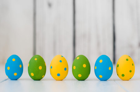 easter eggs standing in a row on a white wooden background