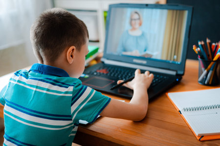 Distance learning online education. A schoolboy boy studies at home and does school homework. A home...