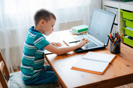 Distance learning online education. A schoolboy boy studies at home and does school homework. A home...