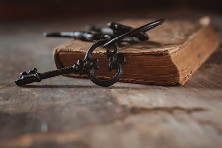 old vintage keys on an old battered book, antique wooden background. The concept of mystery and discovery, answers to questions, a clue.の写真素材