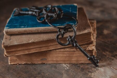 old vintage keys on an old battered book, antique wooden background. The concept of mystery and discovery, answers to questions, a clue.の写真素材