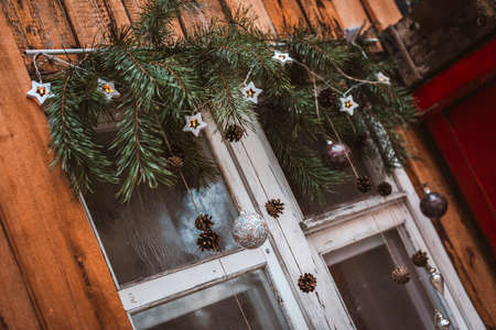 festive new year window decoration with fir branches, garlands and cones. Christmas decorations: Merry Christmas sign and baubles on the window sillの写真素材