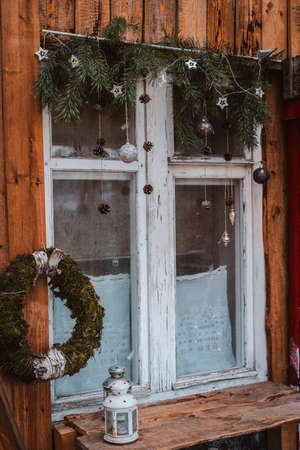 festive new year window decoration with fir branches, garlands and cones. Christmas decorations: Merry Christmas sign and baubles on the window sillの写真素材