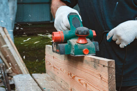 Close-up view of unrecognizable carpenter hand processing wooden board on woodworking machineの写真素材