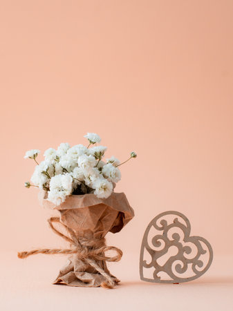 miniature bouquet of gypsophila is wrapped in kraft paper with patterned heart. Greeting card on Women's Mother's Day, March 8, Valentine's Dayの写真素材