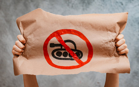 child raises a banner with the inscription no war, standing on the gray concrete background of the studio. No war, stop the war, peaceの写真素材