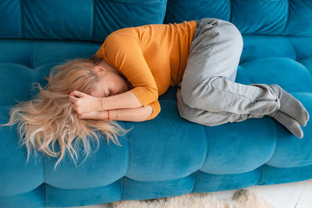 depressed mature woman lying sofa with her arms around herself, covering her head with hands, unhappy woman suffering from insomnia depression, psychological problem,の写真素材