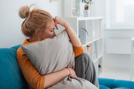 Unhappy lonely depressed woman home, she sitting couch hiding her face pillow, depression conceptの写真素材