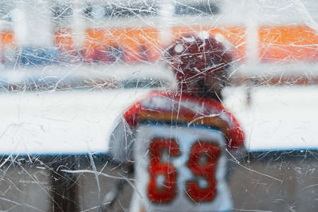Childrens ice hockey. A child hockey player in a protective uniform on the glass side of the ice field.の写真素材