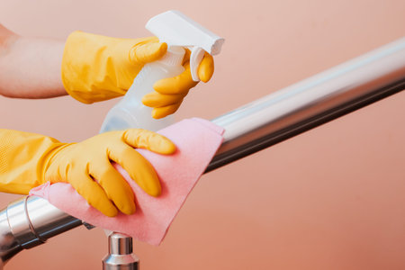 Close-up of a woman cleaning the stair railing. Spring cleaning, disinfection in coronavirus,...