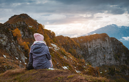happy tourist with a backpack enjoys the view of the cliff after climbing the mountain. The concept of strength, freedom, health, faithの写真素材