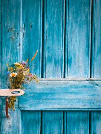 bouquet of wildflowers on the blue door of an old farmhouse. Rustic wood plank background. Free space for text. minimal.の写真素材