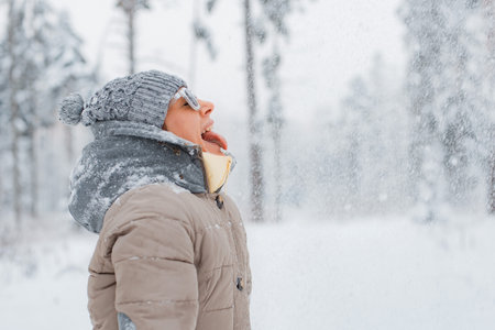 Female dressed fashionable gray wearing sunglasses throws having fun, catching snowflakes with your...