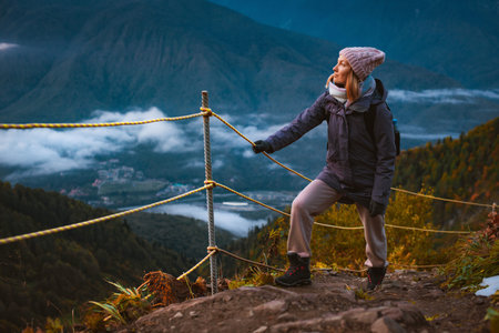 young woman hiking traveler in the mountains in autumn enjoys the view of nature. Mountain climbing,...