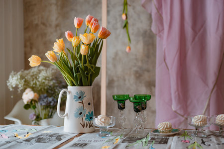 jug with tulips and wine glasses, a romantic meeting, a date, a spring holiday on March 8 and Valentine's day, a party, a newspaper tableclothの写真素材