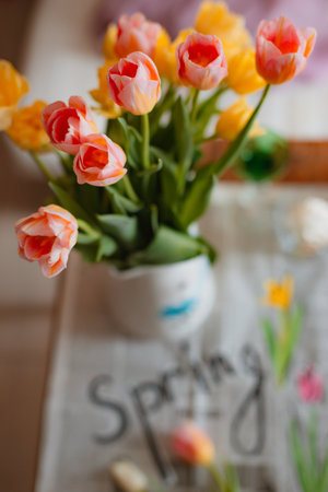bouquet of spring flowers of tulips in a vase on a table with a newspaper with the inscription in...