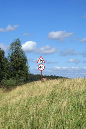 Summer field with road sign on the small hill                  