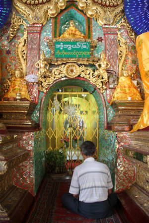 Man seat on the floor in buddhist temple, Shwe DAgon pagoda, Yangon, Myanmarのeditorial素材