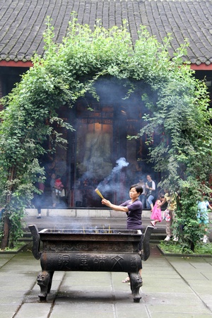 CHENGDU, CHINA - CIRCA JUNE 2012 Woman with burn sticks in taoist templeのeditorial素材
