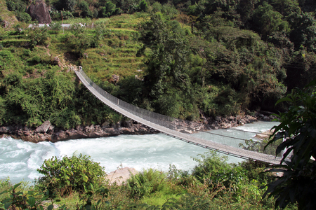 Suspension bridge and mountain river in Nepalの写真素材