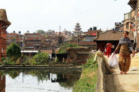 BHAKTAPUR, NEPAL - CIRCA NOVEMBER 2013 Woman walk near pond のeditorial素材