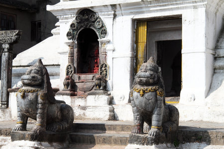 Stone lions near white stupa in Patan, Nepal