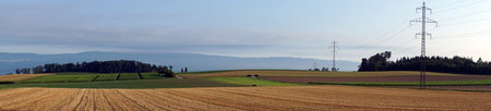 Panorama of pylons with electrical wire on the farm field in Switzerland