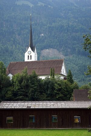 GISWIL, SWITZERLAND - CIRCA AUGUST 2015 Church and green pasture near the mountainのeditorial素材