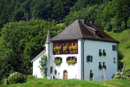 BAUEN, SWITZERLAND - CIRCA AUGUST 2015 White farm house and mountaiinのeditorial素材