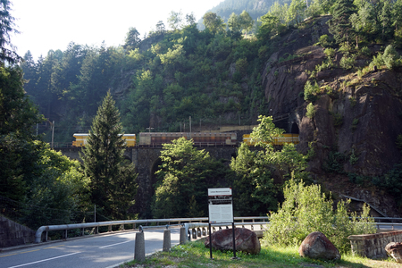 Highway and cargo train on the railway bridge near mountain in Switzerlandのeditorial素材