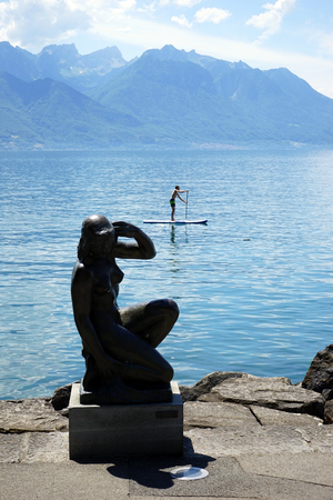 MONTREUX, SWITZERLAND - CIRCA JULY 2018 Paddle serfing and sculpture on the bank of lake Genevaのeditorial素材