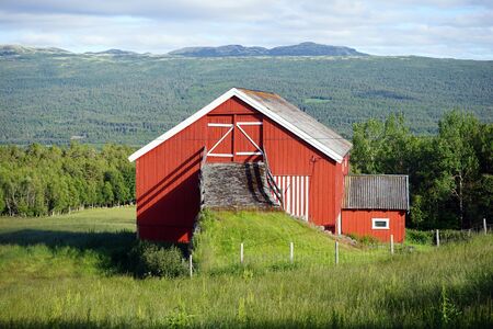 Red wooden house on the slope in Norwayの写真素材