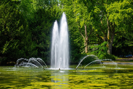 A fountain with water shooting out of it in a park. The water is spraying out of the fountain in a variety of directionsの写真素材
